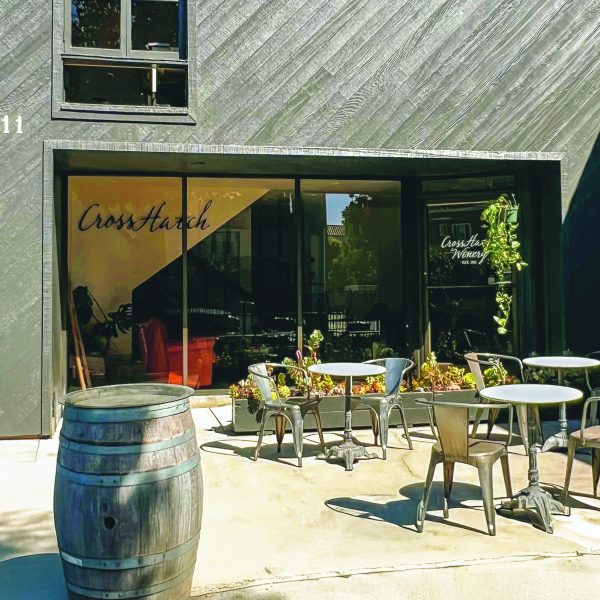 the front of CrossHatch Winery's wine tasting room in Santa Barbara. a dark front with a big glass window and some seating outside on a patio